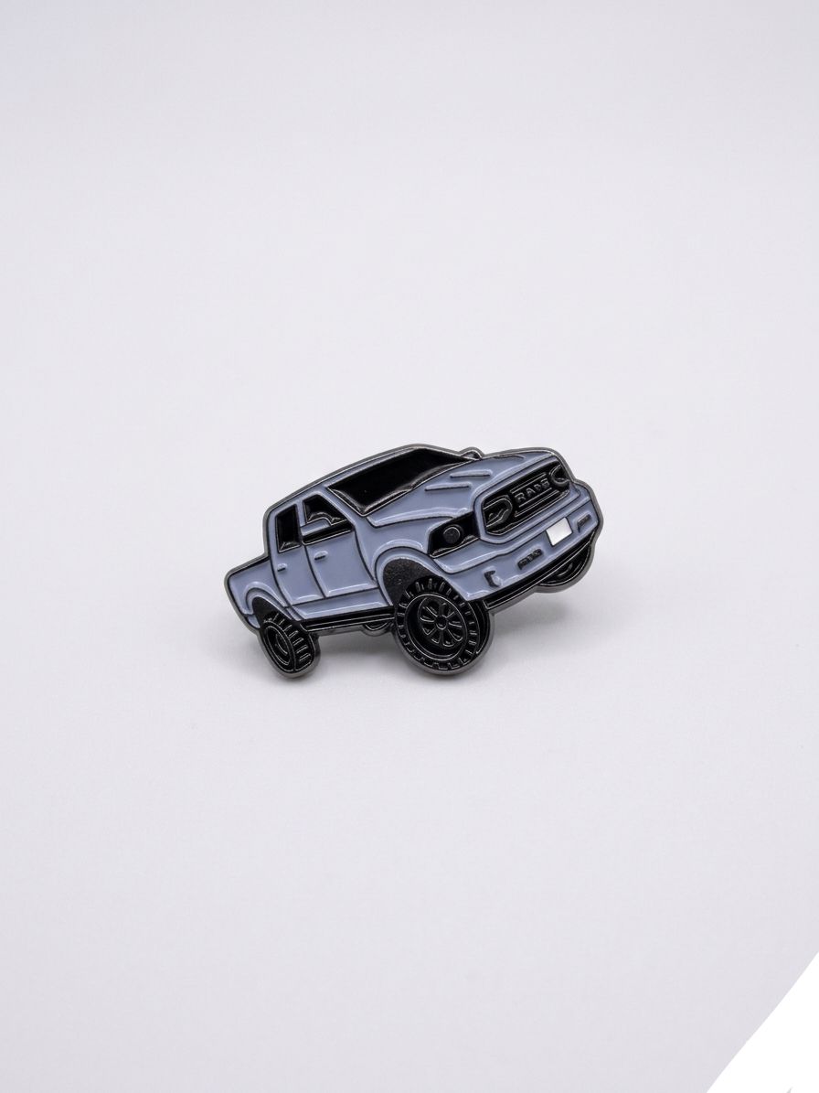 Gray truck-shaped enamel pin on a light gray background QATAR PRICE